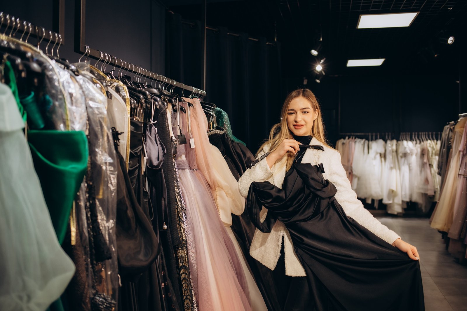 Beautiful girl and her friend choosing clothes for high school prom in shop