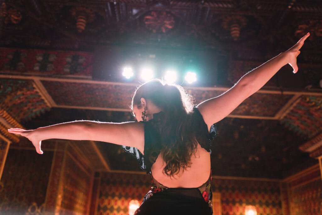 Young woman performing a solo prom dance on stage under bright lights, celebrating with confidence and style